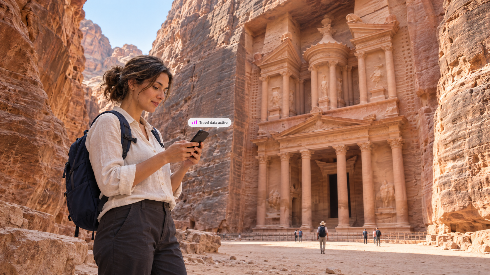A traveler uses a smartphone beside Petra’s Treasury in Jordan, surrounded by rose-colored sandstone cliffs, illustrating easy mobile connectivity with a duasim travel eSIM in the Middle East.
